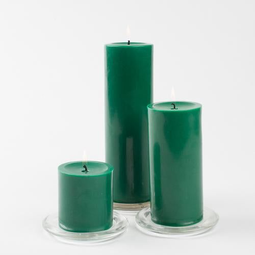 three green candles sitting next to each other on top of a glass plate and white background