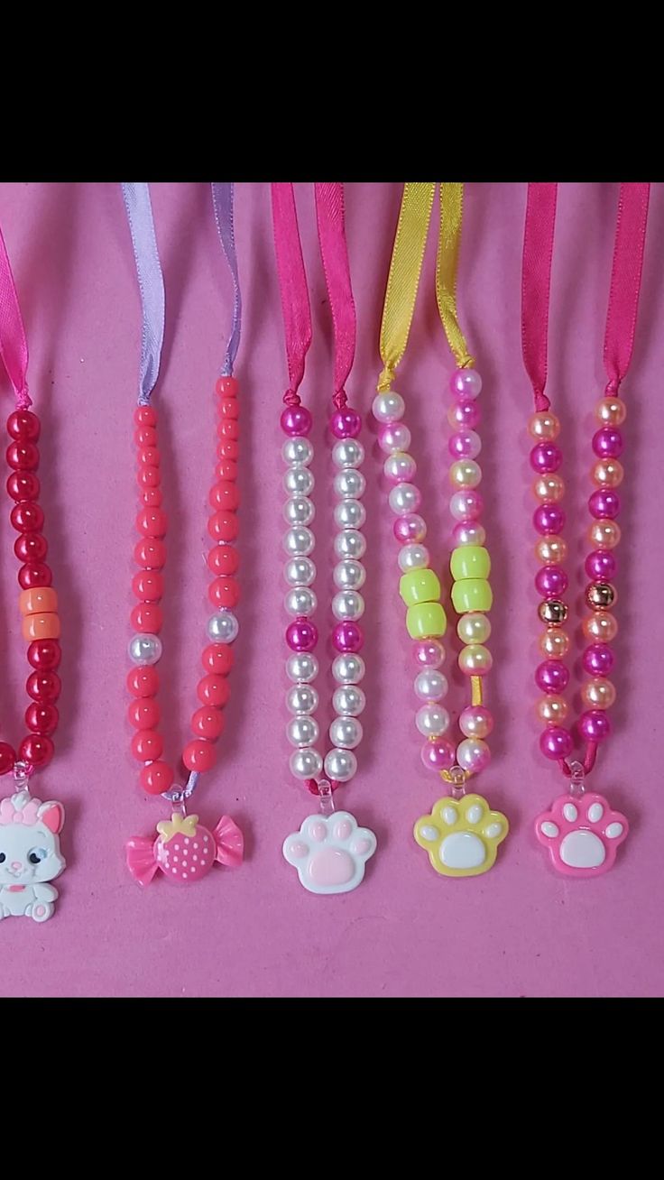 there are many different necklaces on the pink table with hello kitty charms hanging from them