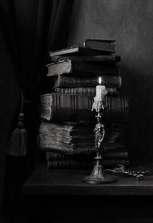 a stack of books sitting on top of a table next to a candle