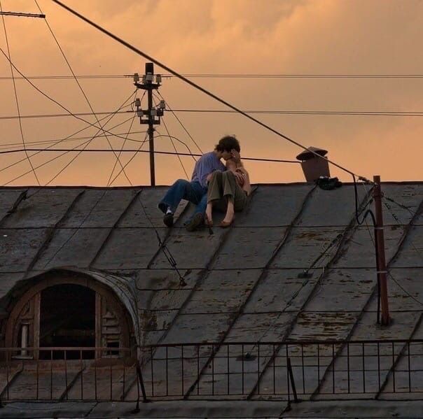 two people sitting on the roof of an old building