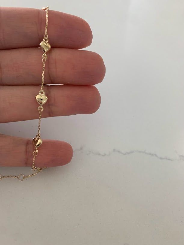 This 14K genuine gold puffed heart charm bracelet is an adjustable 5.5"-6" bracelet, perfect for smaller wrists and toddlers. Its genuine gold material is of high quality, ensuring long-lasting luxury.♦ Material Type: 14K Genuine Gold♦ Available Colors: Gold♦ Bracelet Measurements: Bracelet is exactly 6" inches, including clasp, it has a jump ring at 5.5" as well, hearts are 6MM wide (not including rings on the outer section)♦ Bracelet Average Weight: 1.2 gr MATERIALSAll bracelets are made of 14 Feminine Gold Bracelet, Permanent Bracelet, Real Gold Bracelet, Bracelet Measurements, Charm Bracelet Gold, Gold Bracelet Simple, Gold Heart Bracelet, Wrist Jewelry, Bracelet Simple