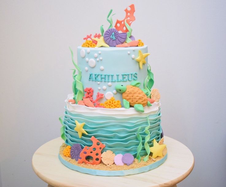 a blue and white cake with under the sea decorations on it's sides, sitting on a table