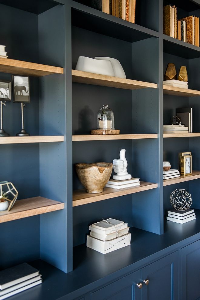 the bookshelves in this room are blue and have wooden shelves with various items on them