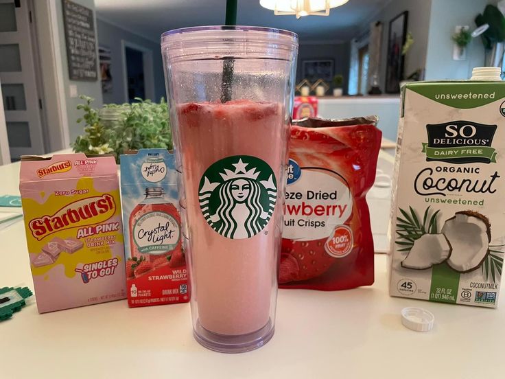 a starbucks drink is sitting on the counter next to some other drinks and snacks,