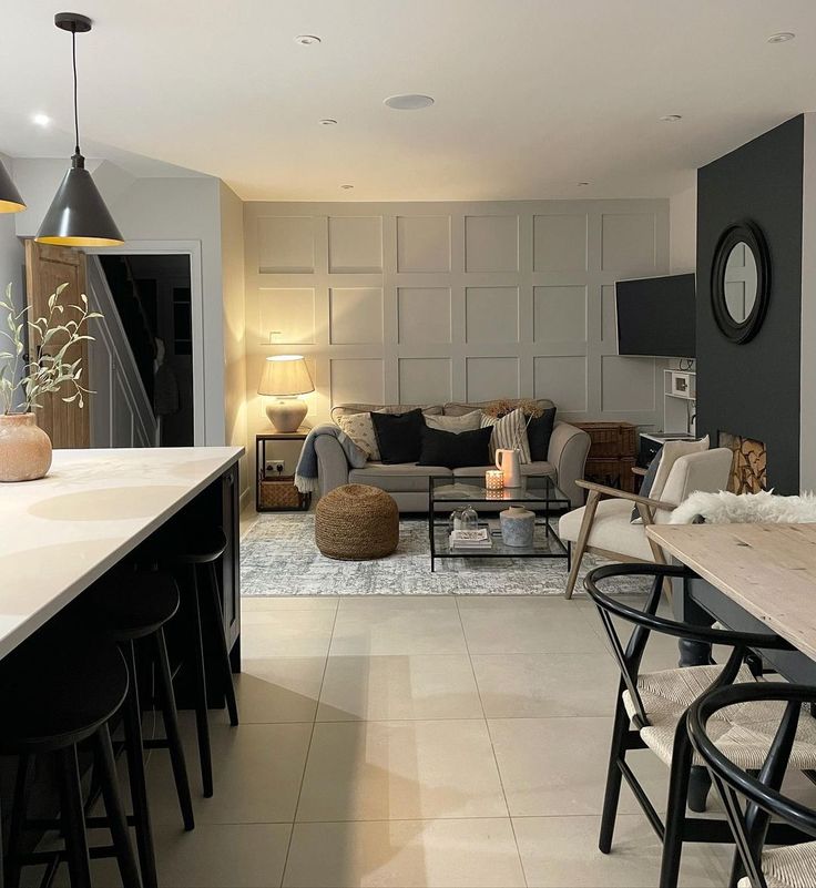 a living room filled with furniture next to a dining table and two lamps on top of it