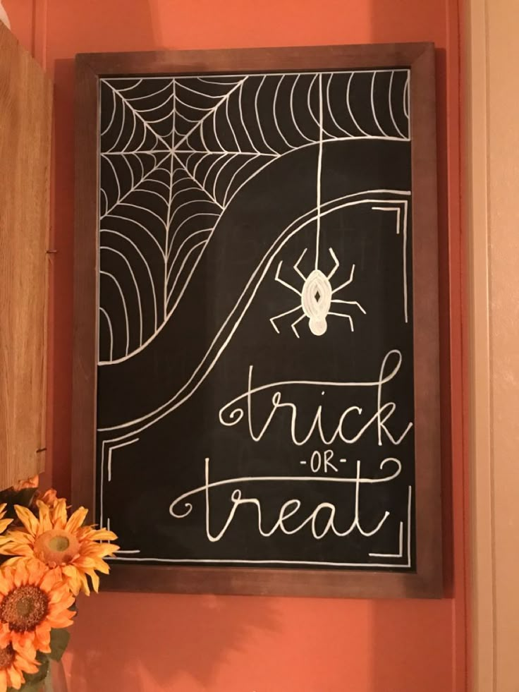 a chalkboard with a spider on it next to a vase filled with sunflowers