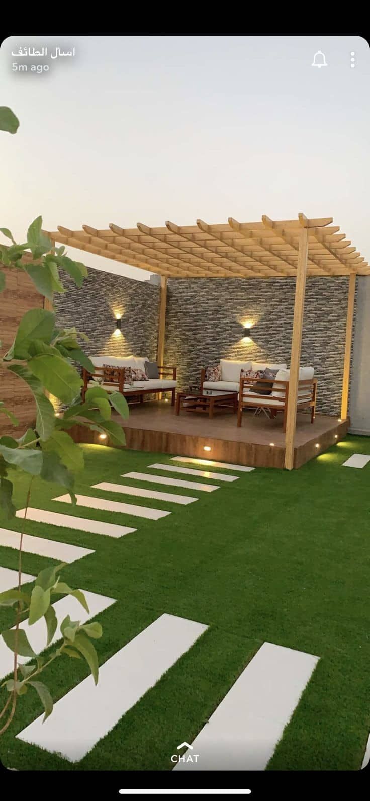 an outdoor living area with grass and white stepping stones on the ground, lit by lights