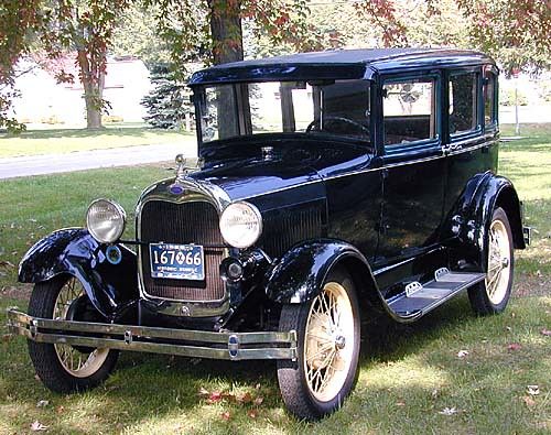 an old black car is parked in the grass