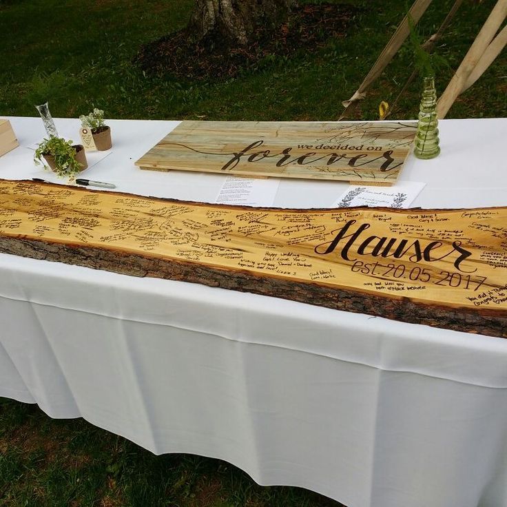 a wooden sign sitting on top of a table next to a white cloth covered table