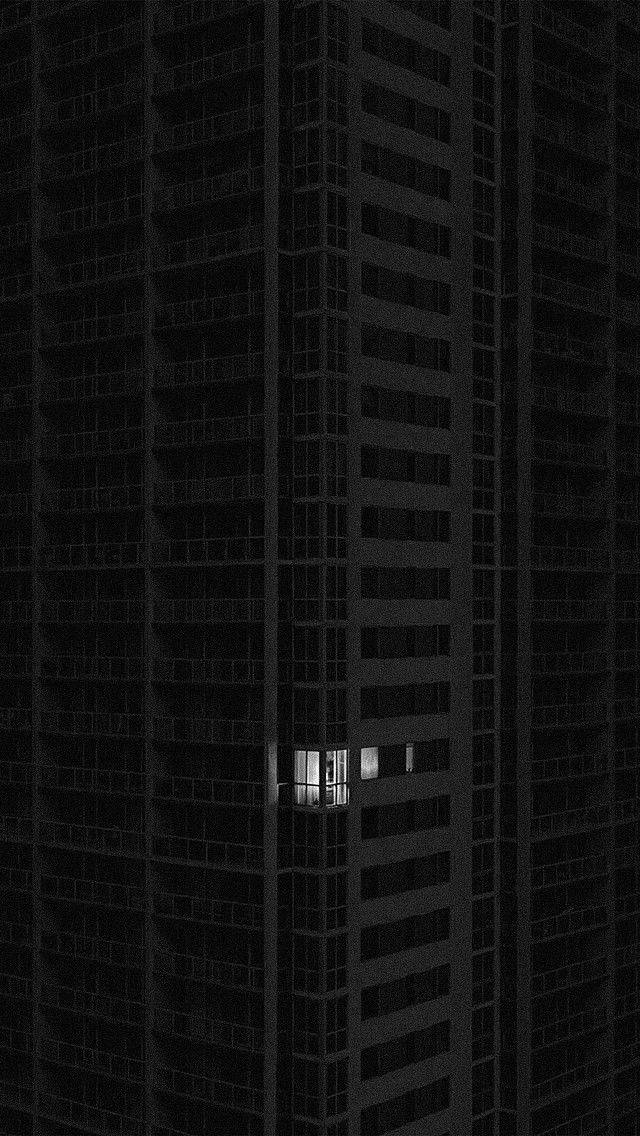 a tall building with two windows in the middle of it's dark night sky