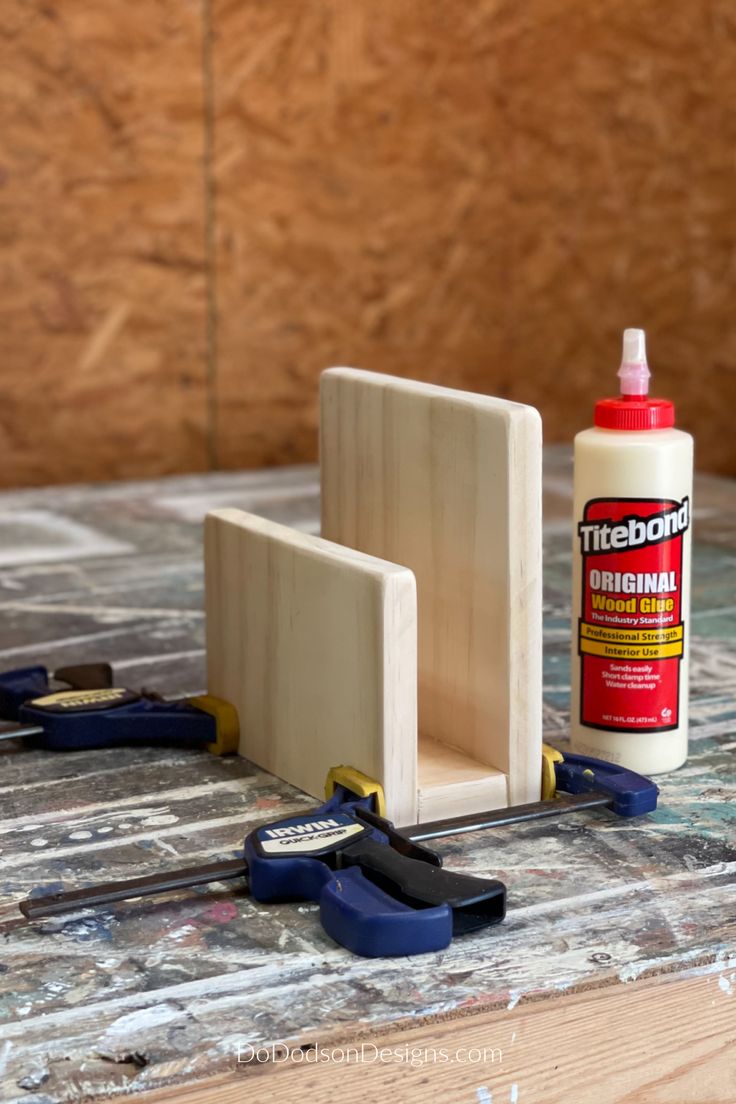 some tools are sitting on a table next to a bottle of glue and pliers