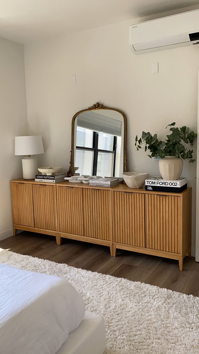 a bedroom with a bed, dresser and mirror on the top shelf in front of it