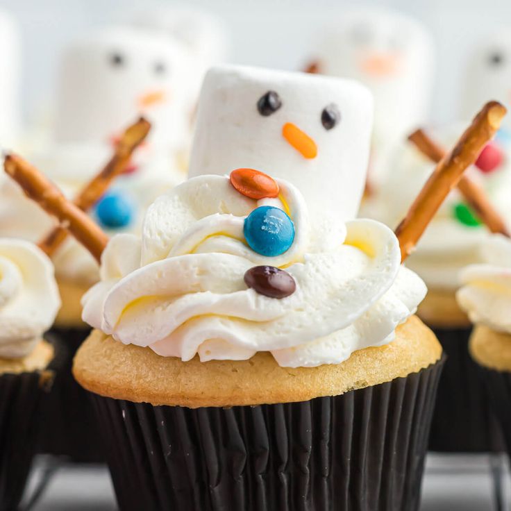 cupcakes decorated with frosting and marshmallows are arranged in the shape of snowmen