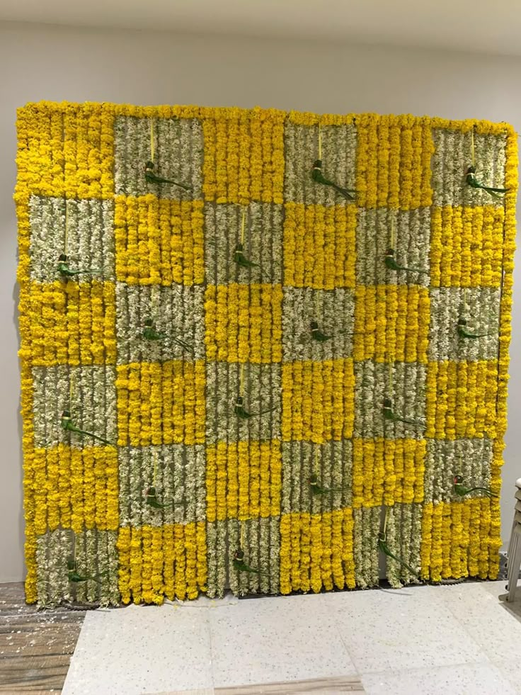 a wall made out of yellow and green flowers in the shape of squares with birds on them