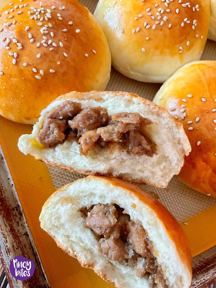 rolls filled with meat and sesame seeds on a yellow tray