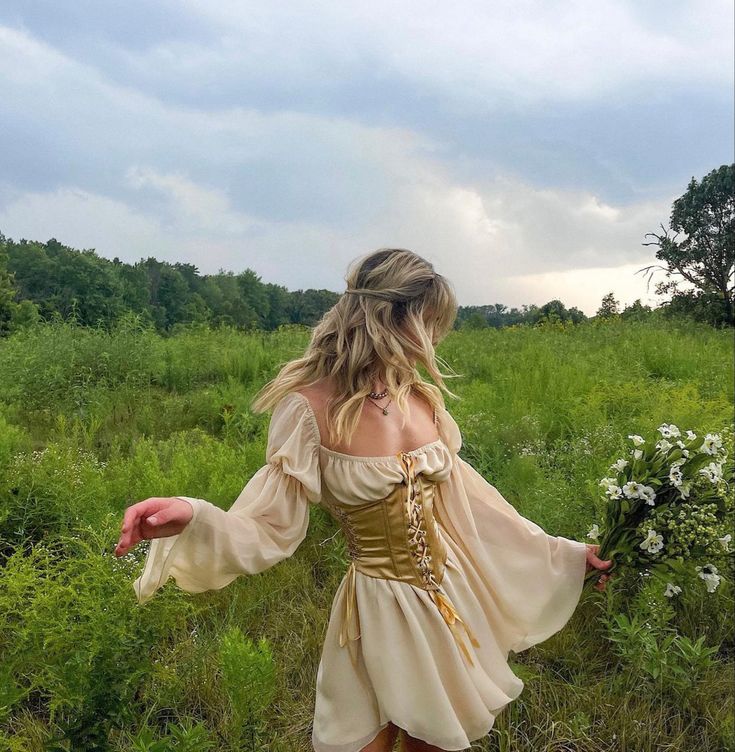 a woman in a dress is walking through the grass