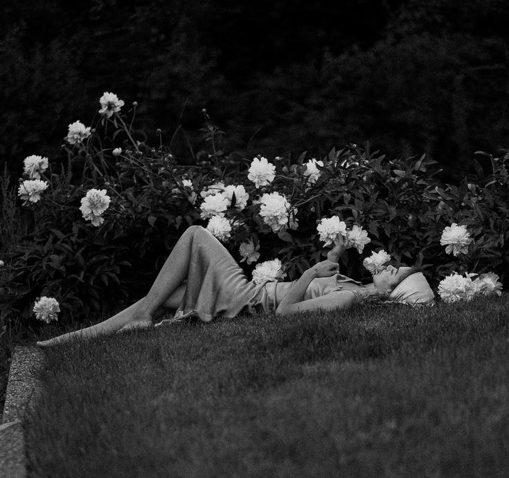 a woman laying on the ground in front of flowers