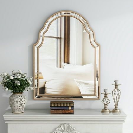 a mirror sitting on top of a mantle next to a vase filled with white flowers