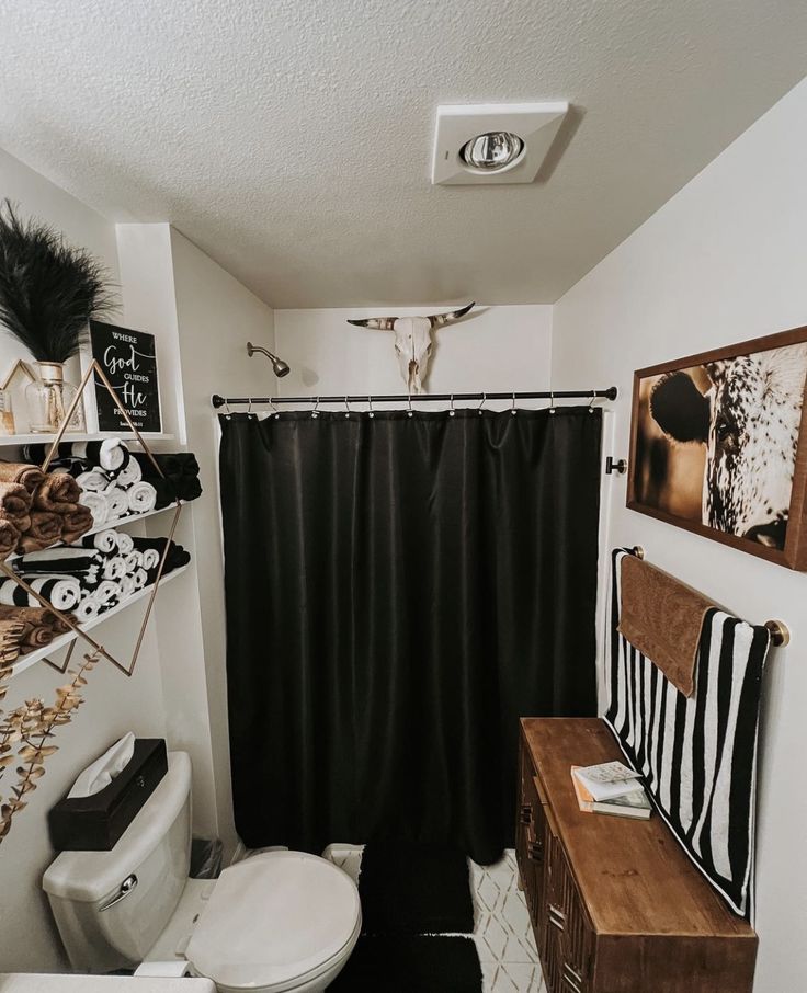 a bathroom with a black and white shower curtain next to a toilet in the corner