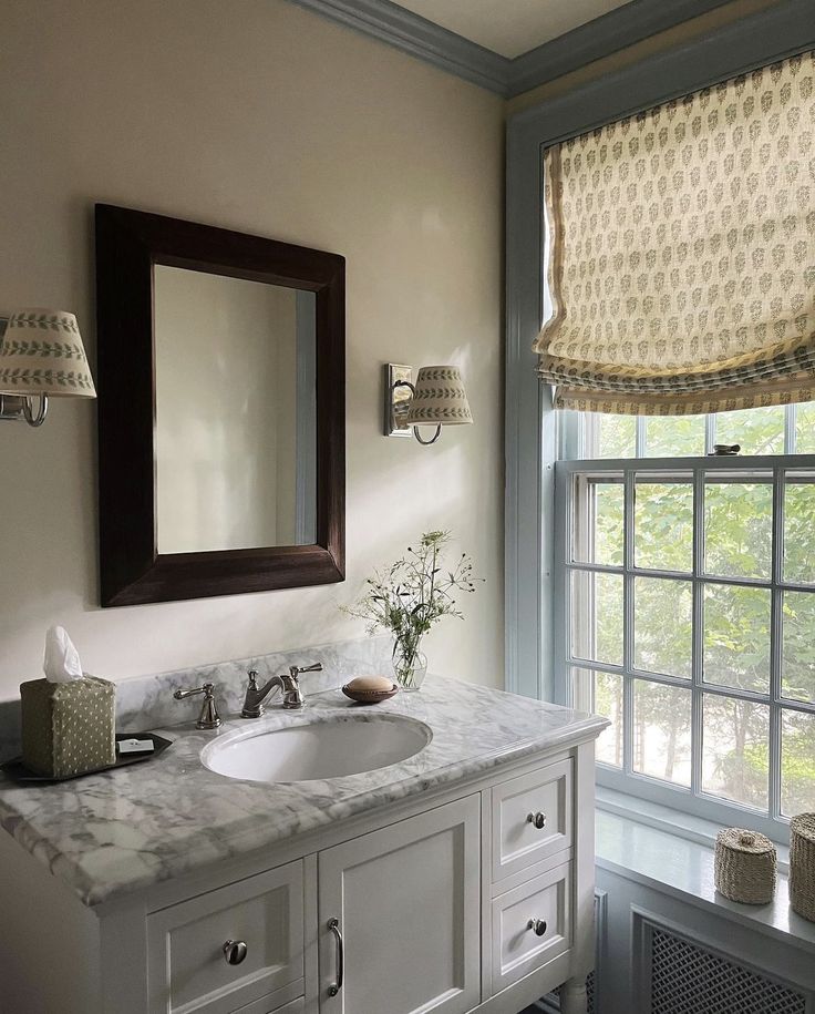 a bathroom with two sinks and a large mirror above it in front of a window