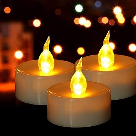 three lit candles sitting next to each other on top of a black surface with lights in the background