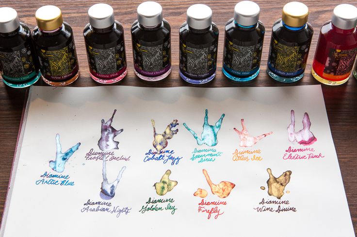 several ink bottles are lined up on a table next to a sheet of paper with different ink colors