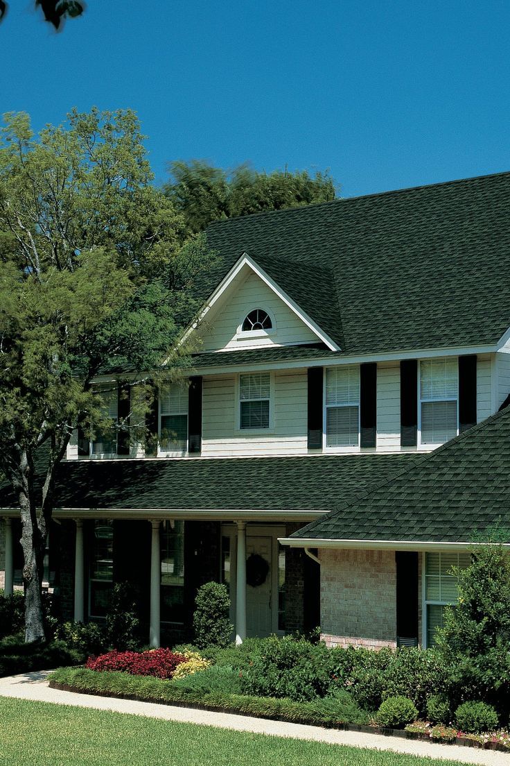 a large white house with black shutters and green grass in front of the house