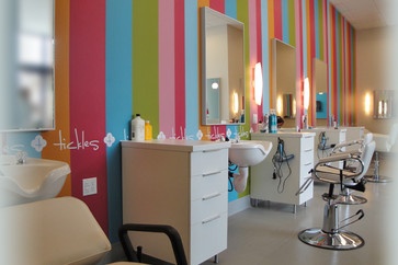 the interior of a hair salon with multicolored striped walls and chairs in front of them