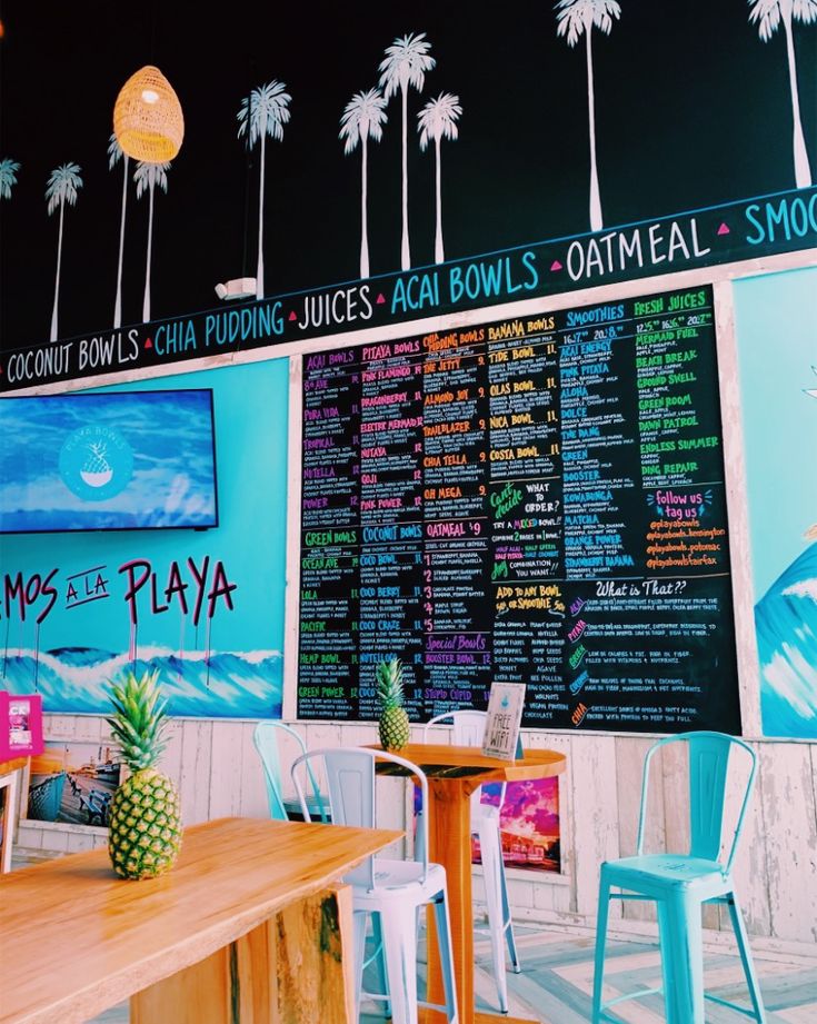 the inside of a restaurant with palm trees on the wall and menus hanging from the ceiling