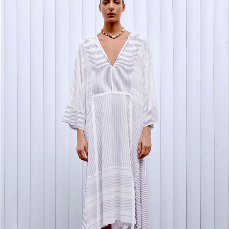 Gorgeous Dress With Round Collar And V Neck Front With Long Sleeves.Contrasting Tie Belt.Asymmetrical Hem. White Asymmetrical Maxi Dress For Vacation, White Asymmetrical Midi Dress For Vacation, Asymmetrical White Maxi Dress For Vacation, Flowy Midi Dress With High-low Hem For Day Out, Chic Asymmetrical V-neck Dress For Beach, White V-neck Viscose Dress, White Maxi Dress With Asymmetrical Hem For Summer, Chic White Viscose Midi Dress, White Summer Maxi Dress With Asymmetrical Hem