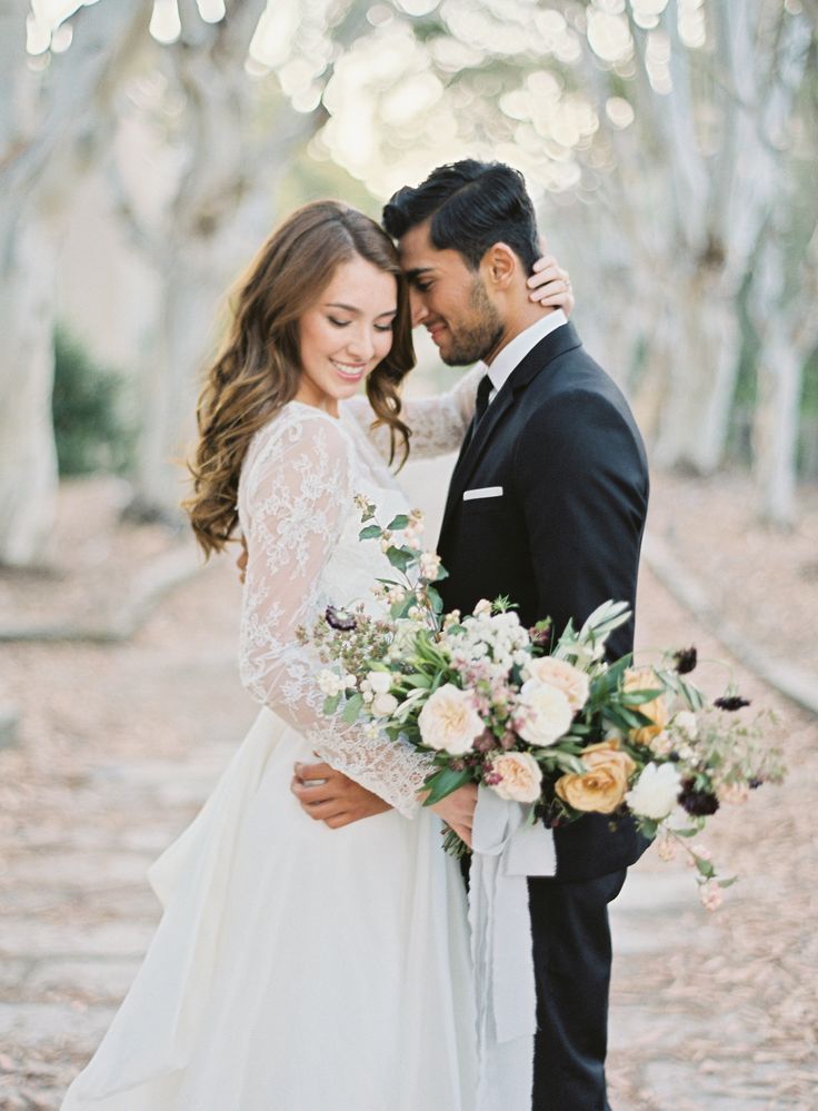 a bride and groom standing in front of trees