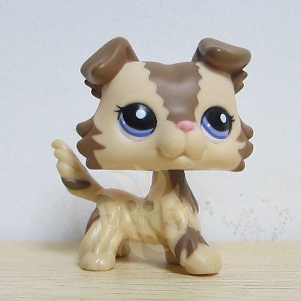 a small toy cat sitting on top of a wooden table next to a white wall