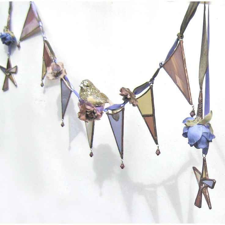 there is a wind chime hanging on the wall with blue flowers and birds in it