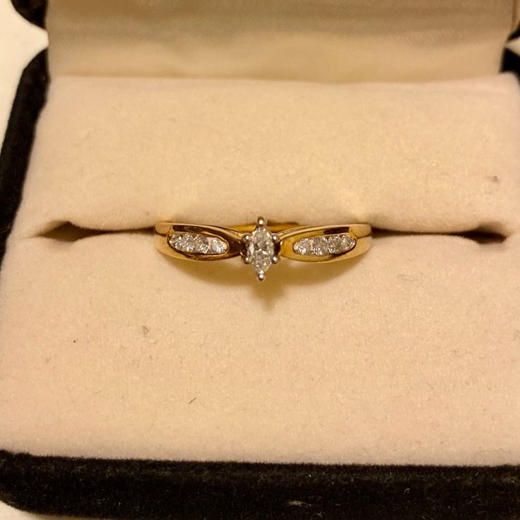 an open box with a gold ring and diamond set in the middle, sitting on a white surface