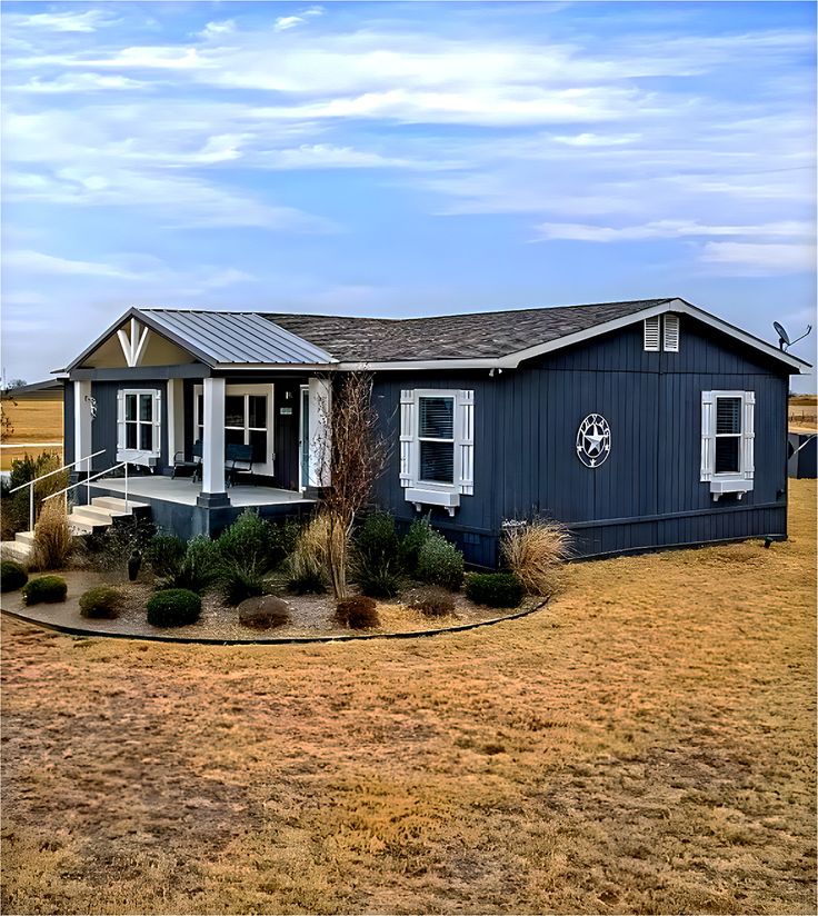 a blue house with white trim and windows in the front yard on a sunny day