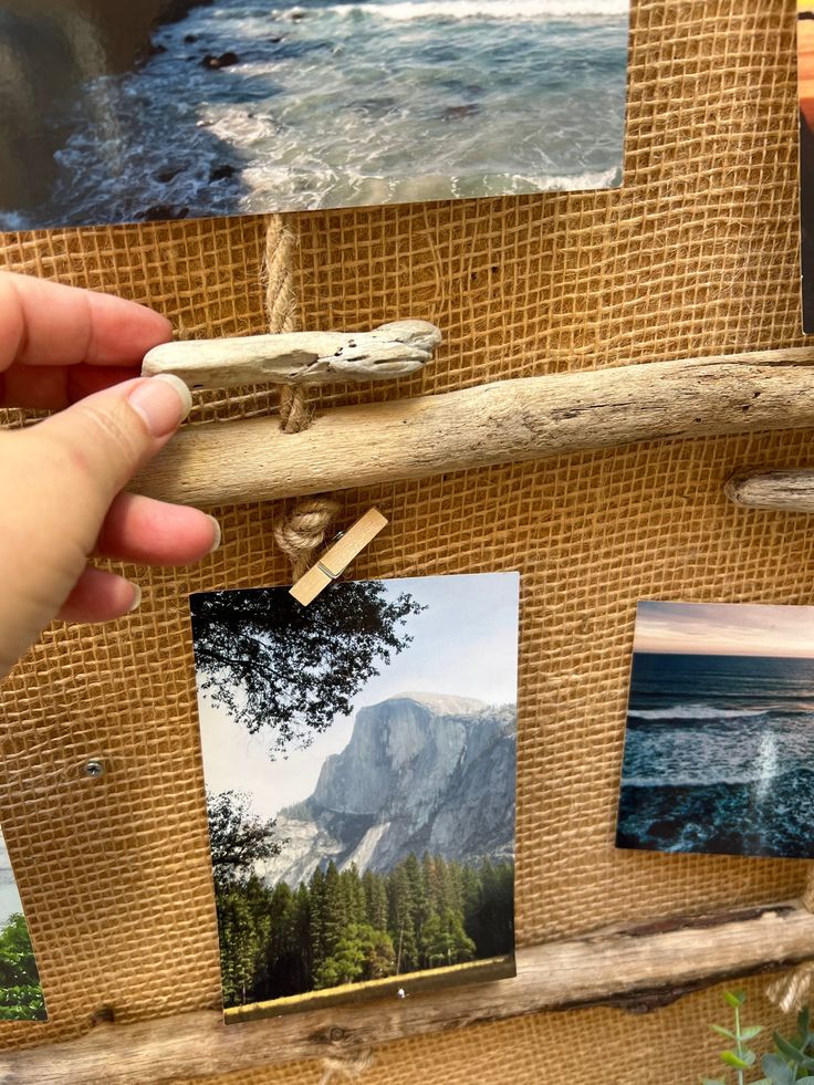 a person is holding up photos on a wooden frame with some stickers attached to it