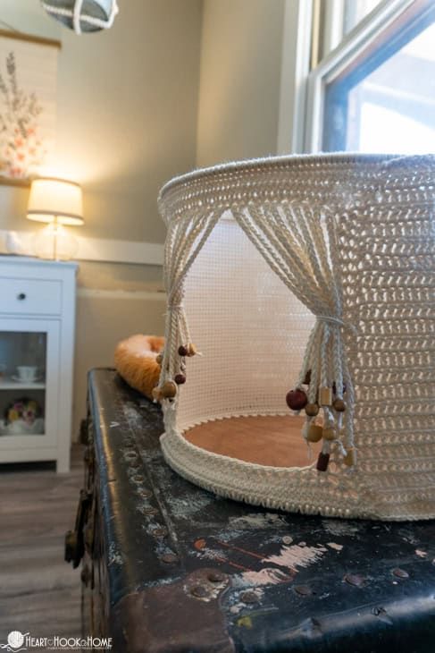 a white lamp shade sitting on top of a wooden table next to a cat bed