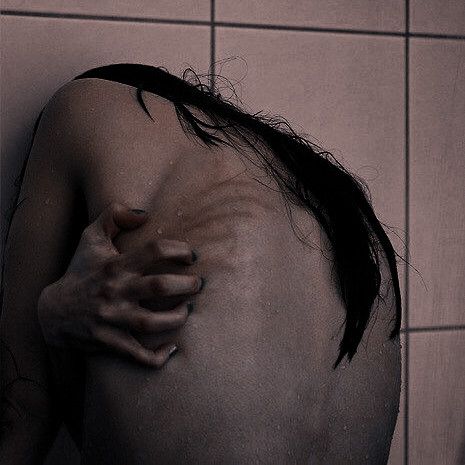 a person with their arm wrapped around the back of his head in a shower stall