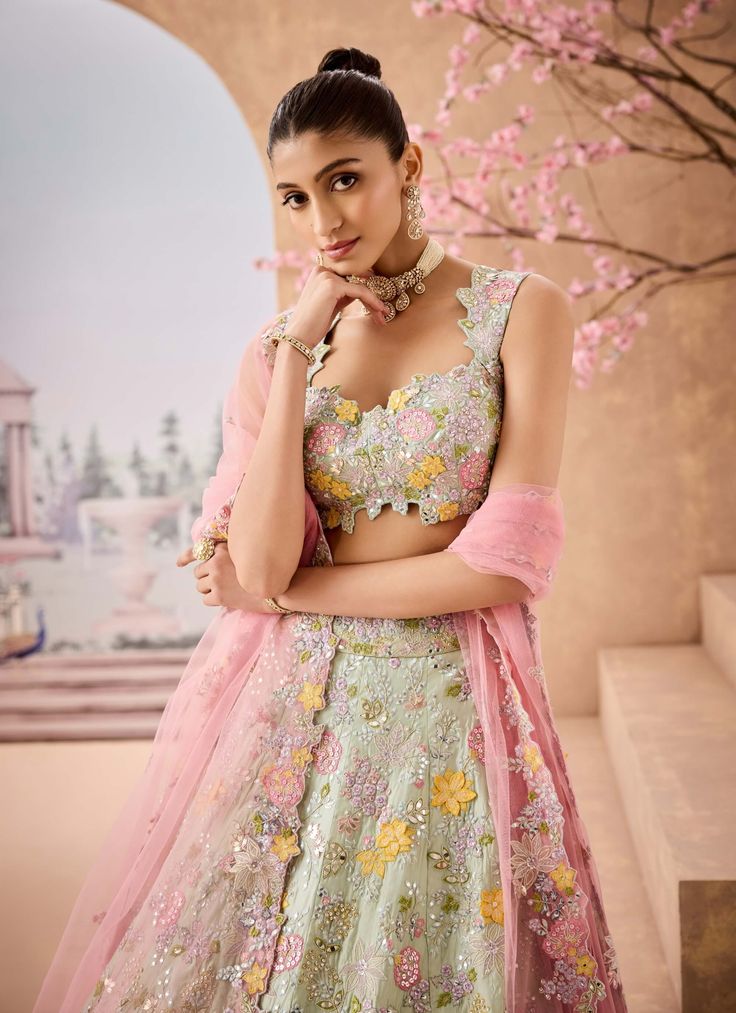 Introducing a delicate mint lehenga adorned with exquisite 3d handcrafted embroidered flowers. Embellished with sequins, mirrors, thread, and badla work, this ensemble radiates charm and sophistication. Paired with a soft pink dupatta, it’s the perfect choice for those seeking a graceful look for special occasions. Georgette Lehenga With Floral Embroidery For Reception, Designer Pista Green Sharara With Floral Embroidery, Pista Green Embellished Semi-stitched Lehenga, Embellished Floor-length Pista Green Lehenga, Pista Green Embellished Anarkali Set For Wedding, Party Wear Floral Embroidered Floor-length Lehenga, Party Wear Floor-length Lehenga With Floral Embroidery, Pista Green Lehenga With Intricate Embroidery For Party, Pista Green Embellished Lehenga For Reception