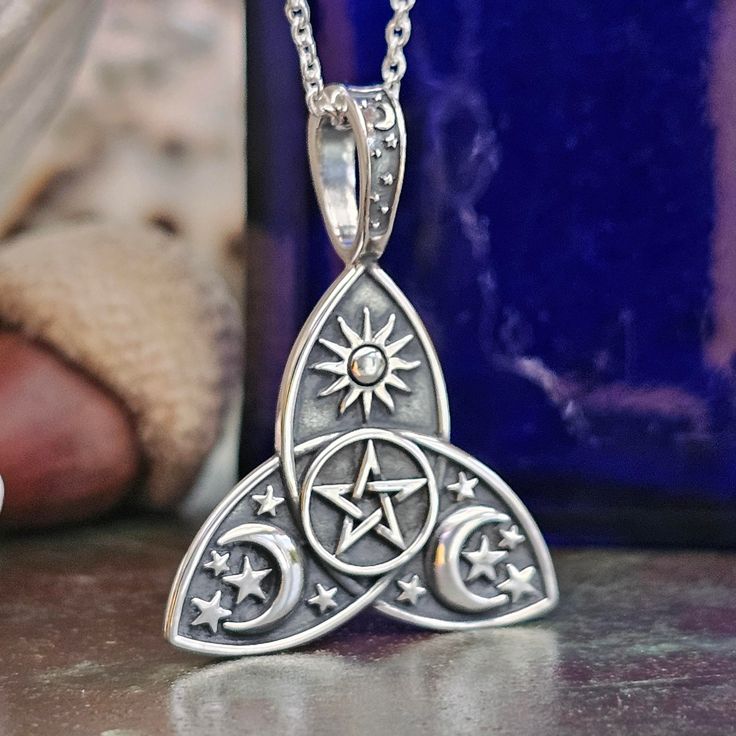 a silver pendant on a table next to a blue vase and a pair of shoes