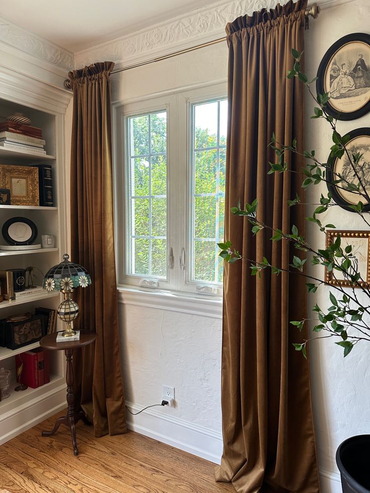 a living room filled with furniture and a window covered in brown drapes next to a wooden floor