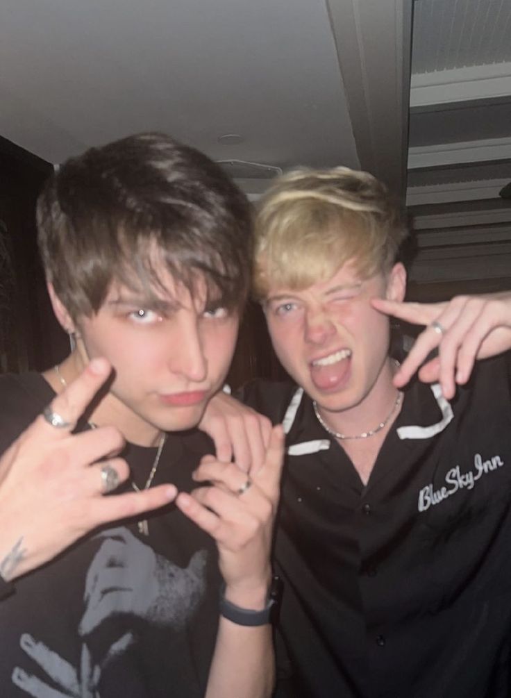 two young men posing for the camera with their fingers in the air and one pointing