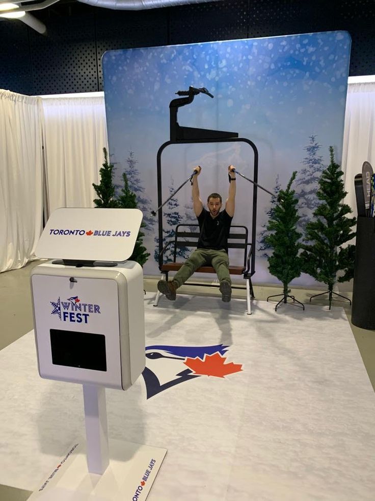 a man sitting on a bench in front of a christmas tree display at a convention