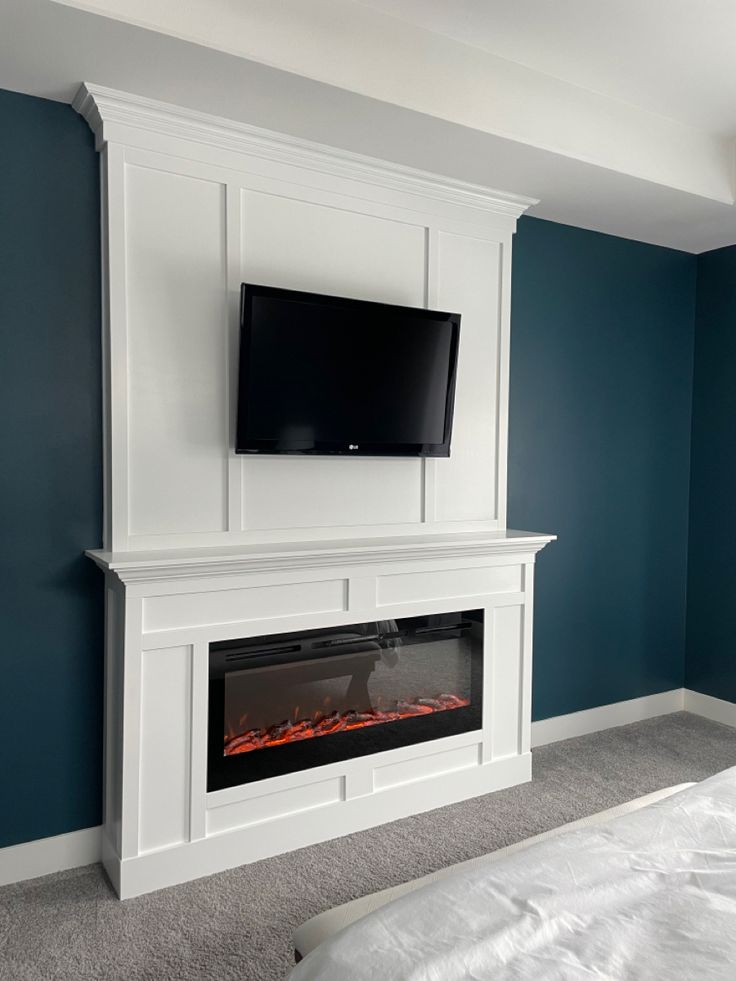 a flat screen tv mounted on the wall above a fireplace in a room with blue walls