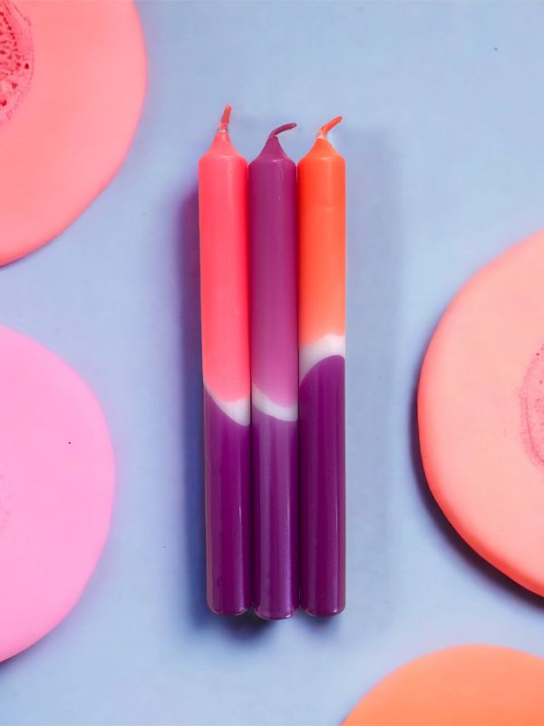 three candles sitting next to each other on top of pink and orange soaps,