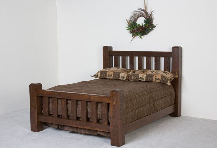 a wooden bed frame with two pillows on top of it and a wreath above the headboard