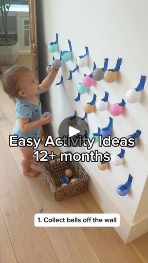 a baby standing next to a wall with magnets on it