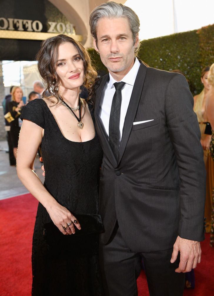 a man and woman in formal wear standing on a red carpet