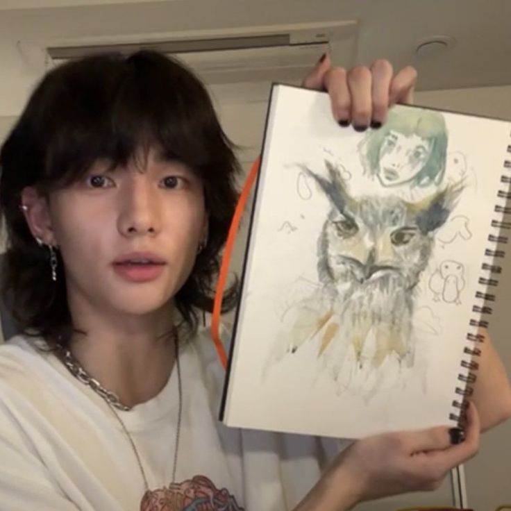 a woman holding up a drawing with an owl on it's face in front of her