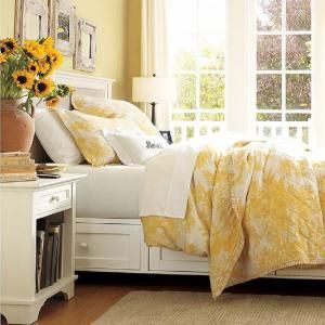 a bedroom with sunflowers in a vase on the end table next to the bed